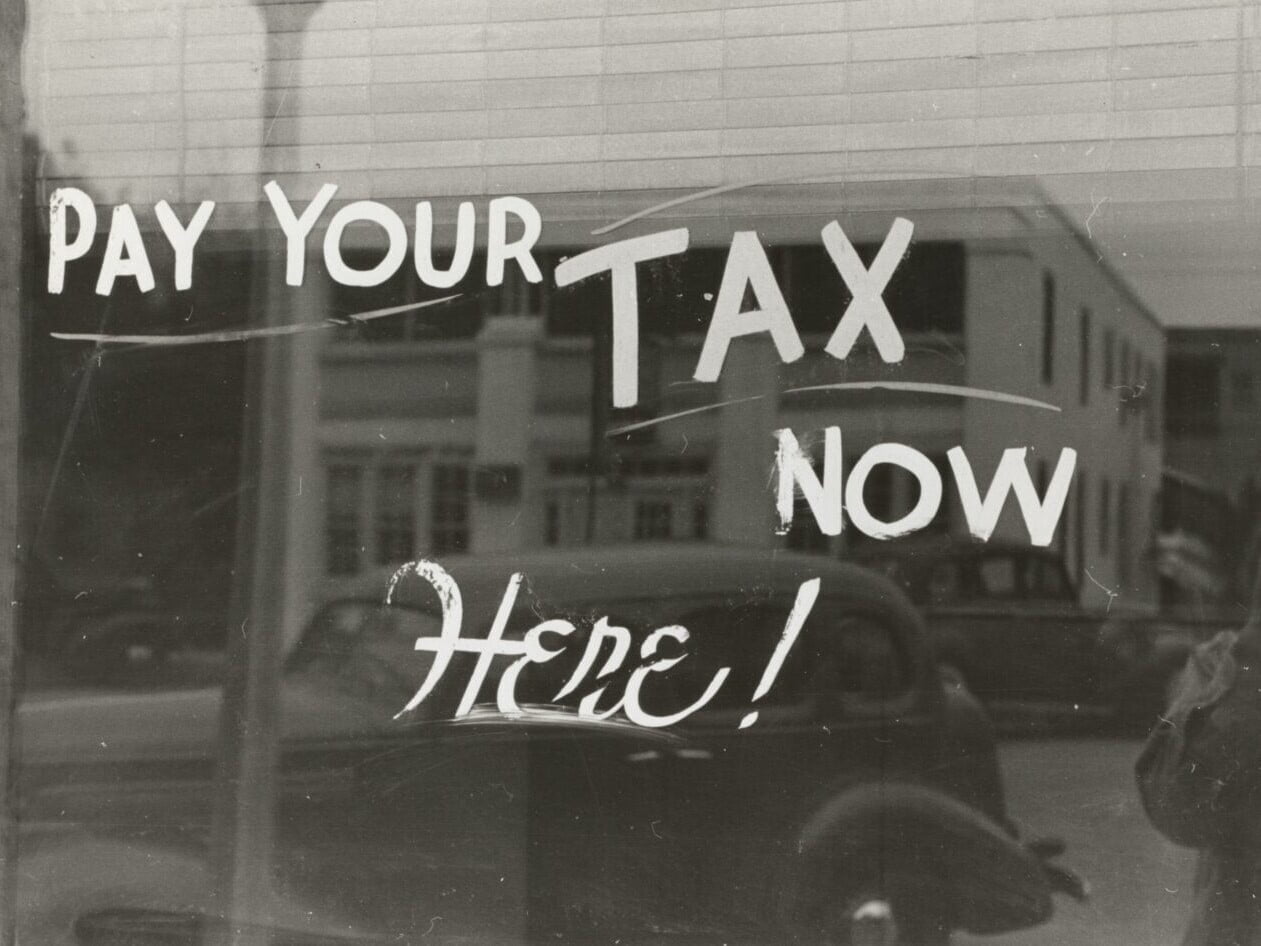 Fenster mit dem Satz «Pay your tax now here!» darauf in schwarzweiss.
