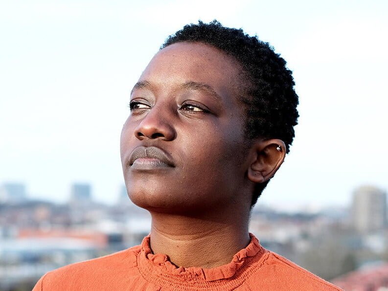 Porträt von Jackie Karuti. Sie trägt eine orangene Bluse.